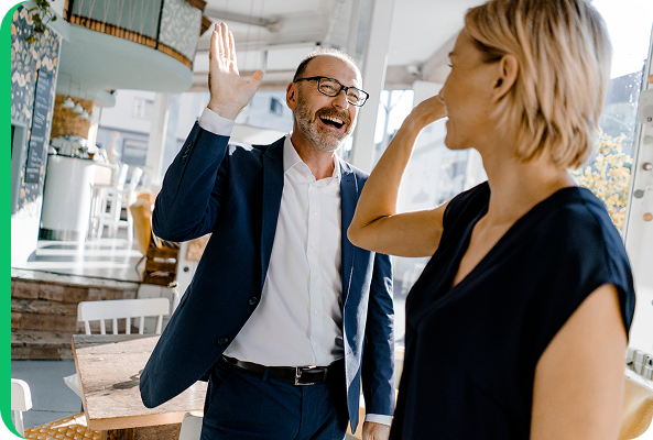 Two professionals giving a high-five in a bright workplace, illustrating successful collaboration and cost savings for a business.